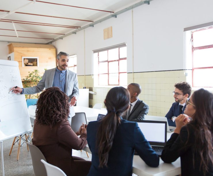 Cheerful speaker talking and looking at distance. Group of employees discussing ideas during presentation of new project at briefing. Business meeting concept